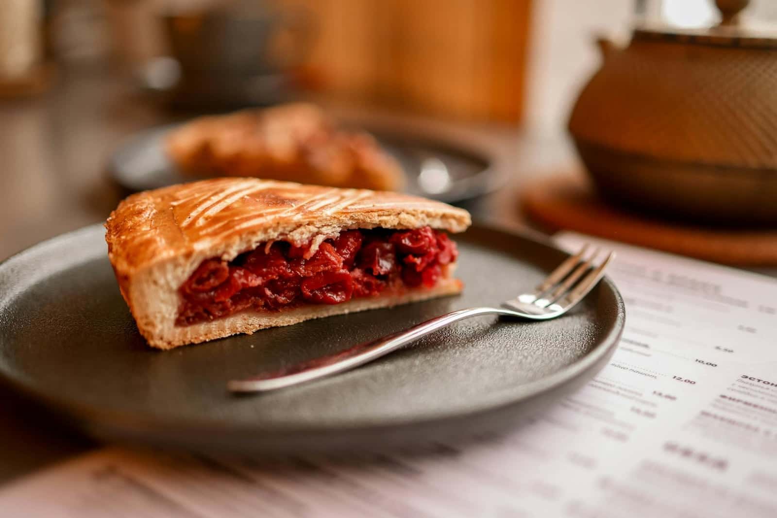 Cherry pie slice with ruby fruit filling and flaky crust served on a plate