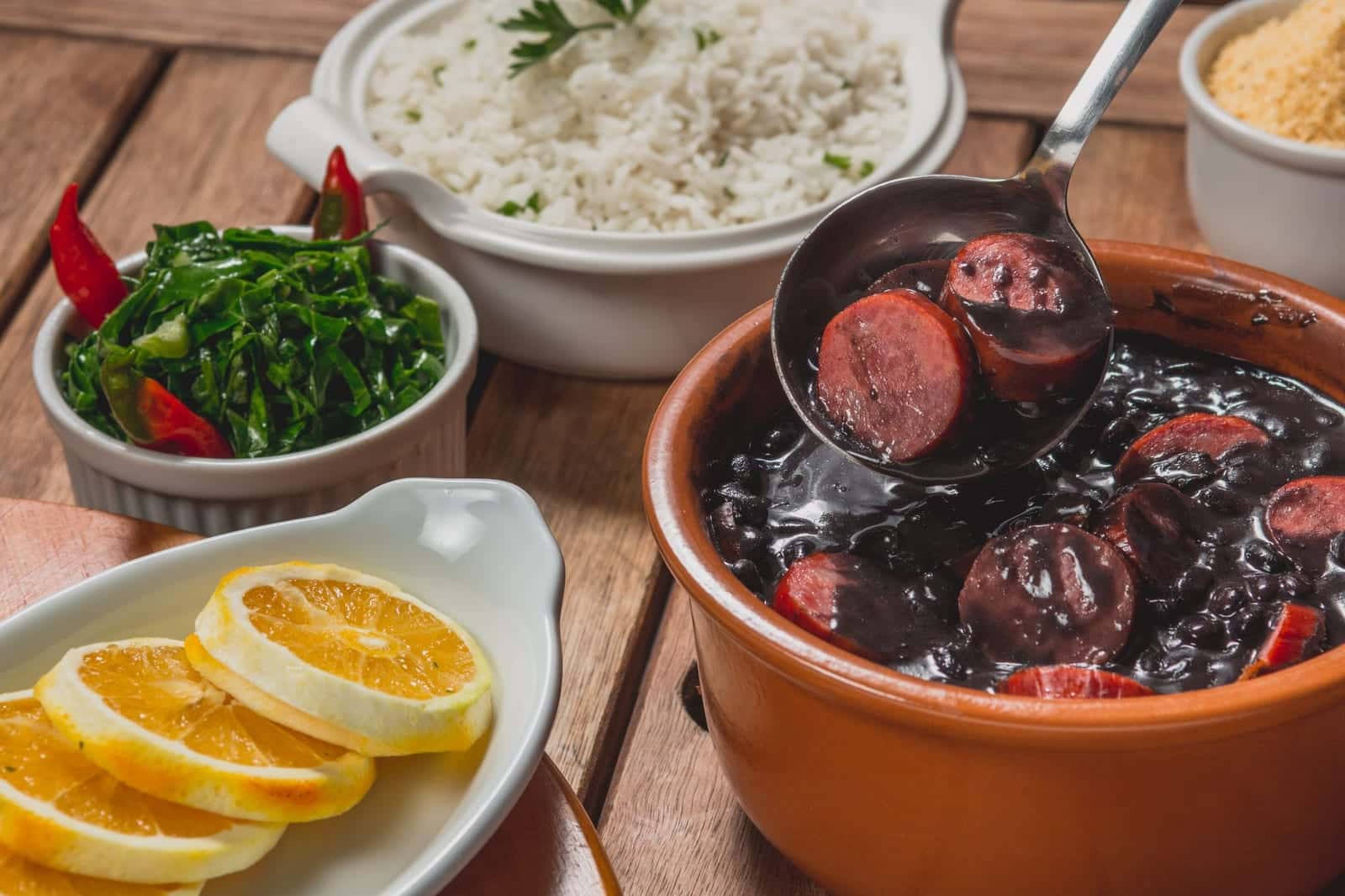 Feijoada, Brazilian black bean and pork stew, served with white rice, collard greens and orange slices