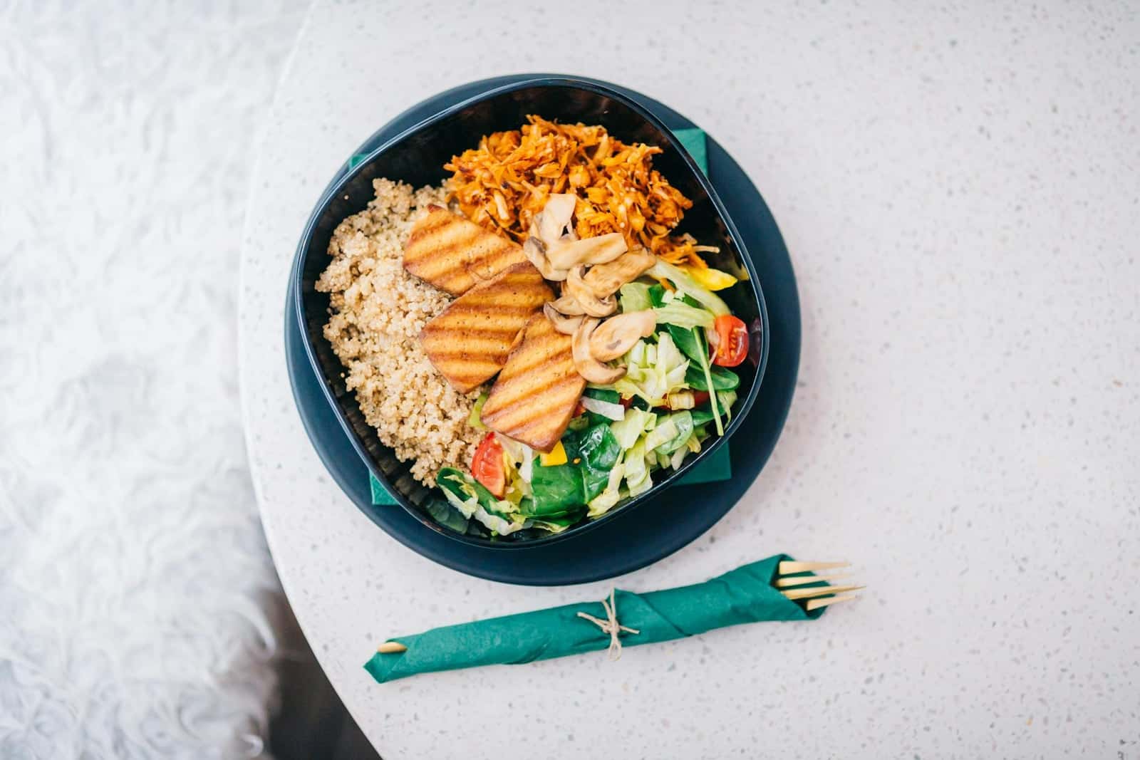 Teriyaki tofu bowl with grains, vegetables, shredded carrots, greens, and sliced tofu