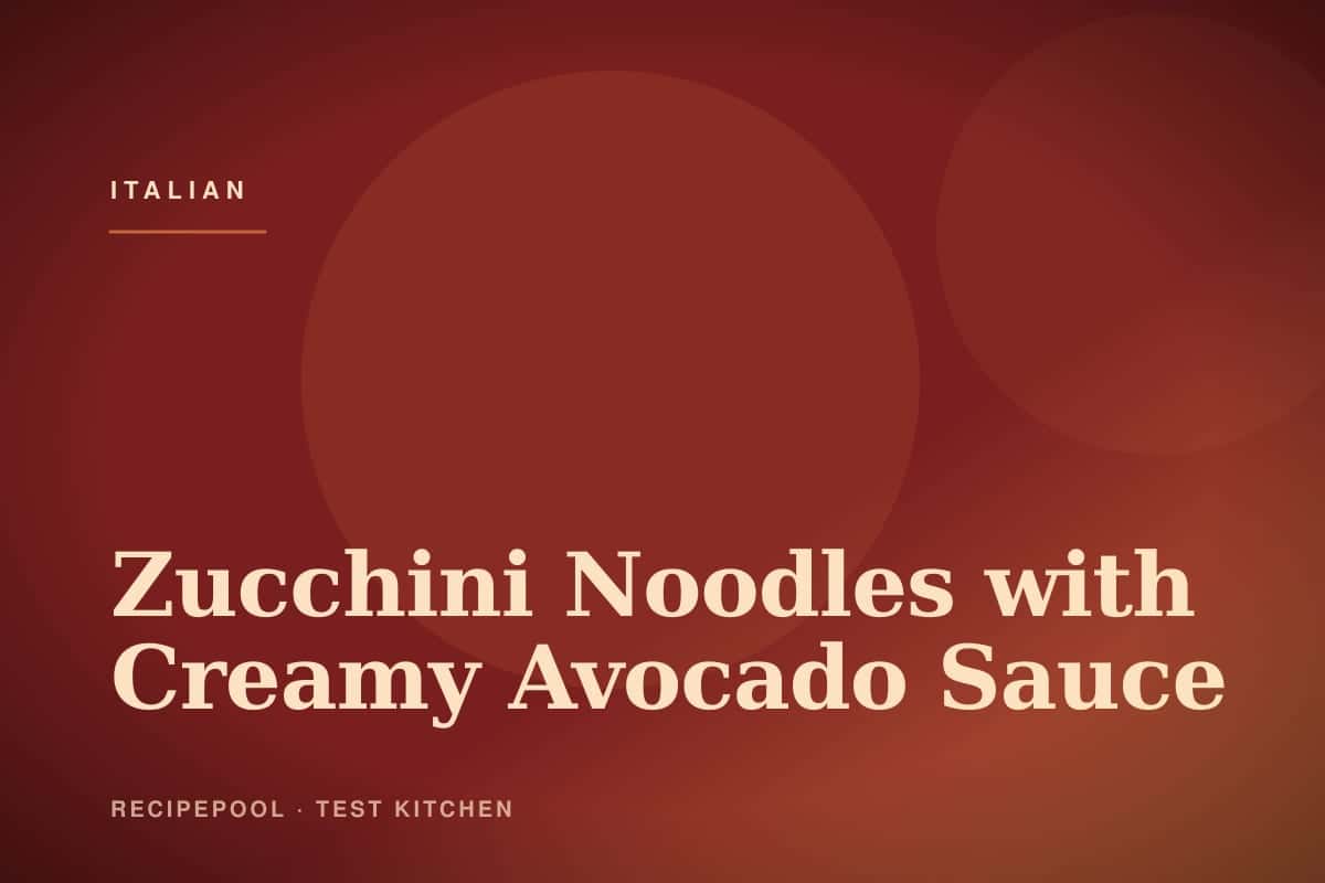 Bowl of zucchini noodles tossed in creamy green avocado sauce with cherry tomatoes