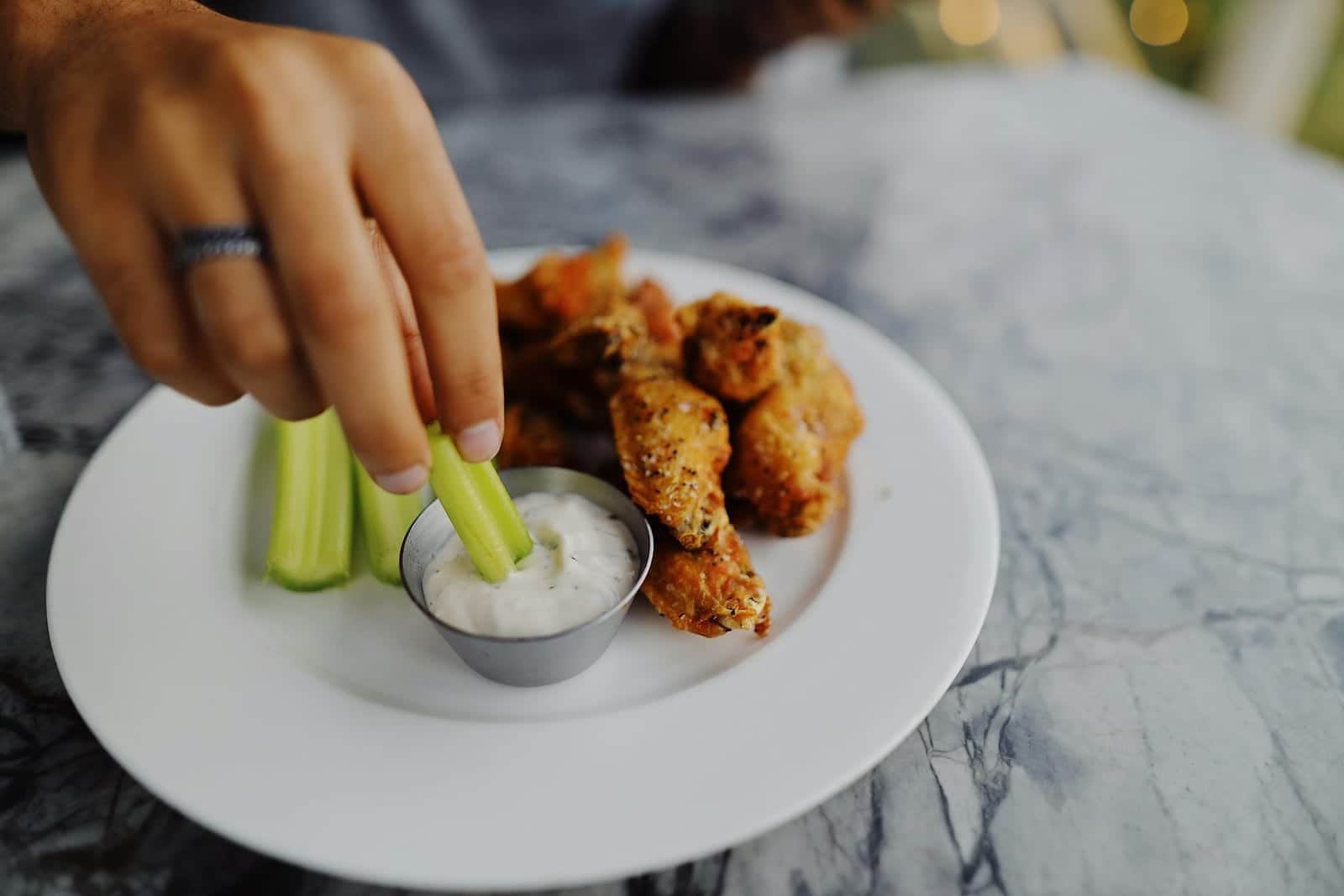 Buffalo chicken dip setup with celery, creamy dip, and spicy chicken pieces on a plate