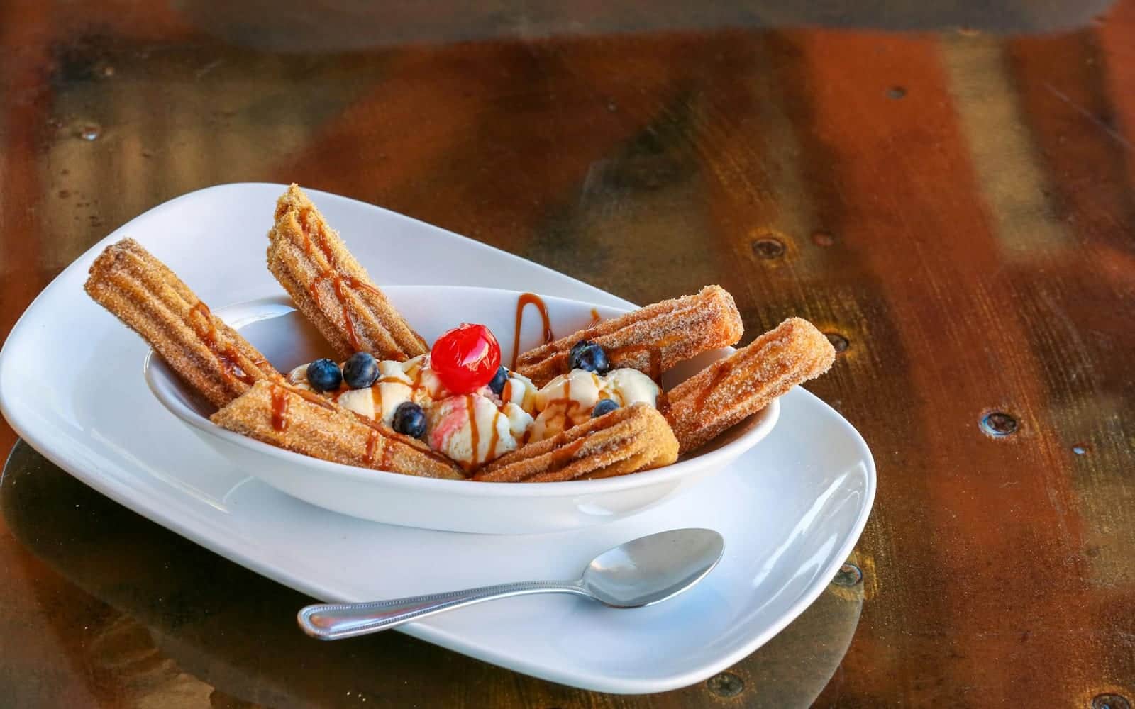 Churro ice cream dessert with churros, ice cream, blueberries, and cherry