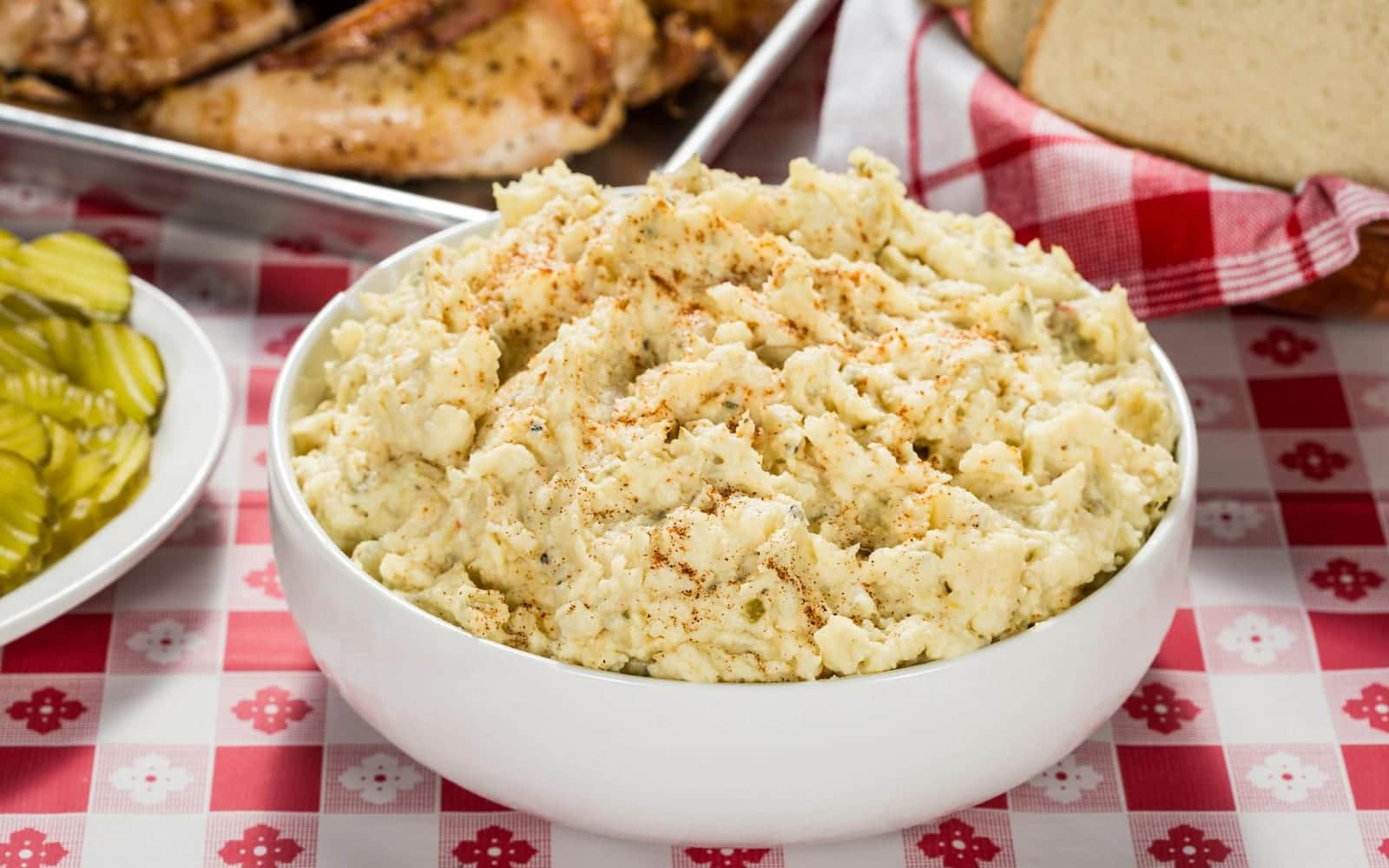 Classic American potato salad in a white bowl on a checkered picnic table