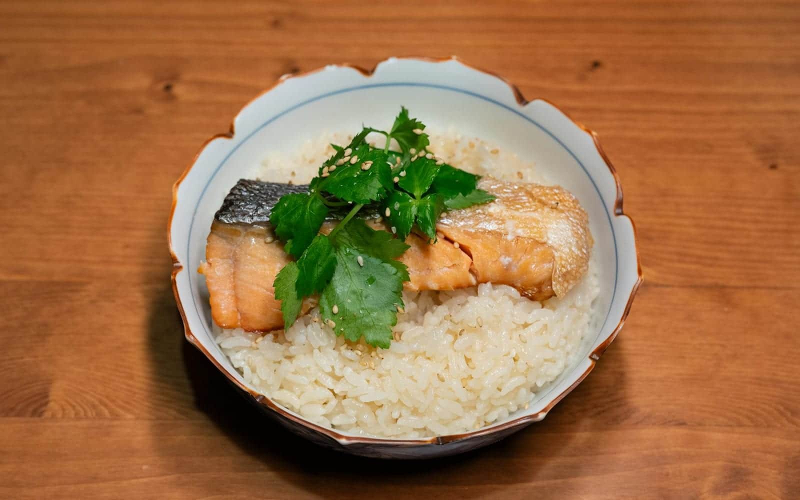 Clean eating salmon bowl with salmon, rice, herbs, and vegetables