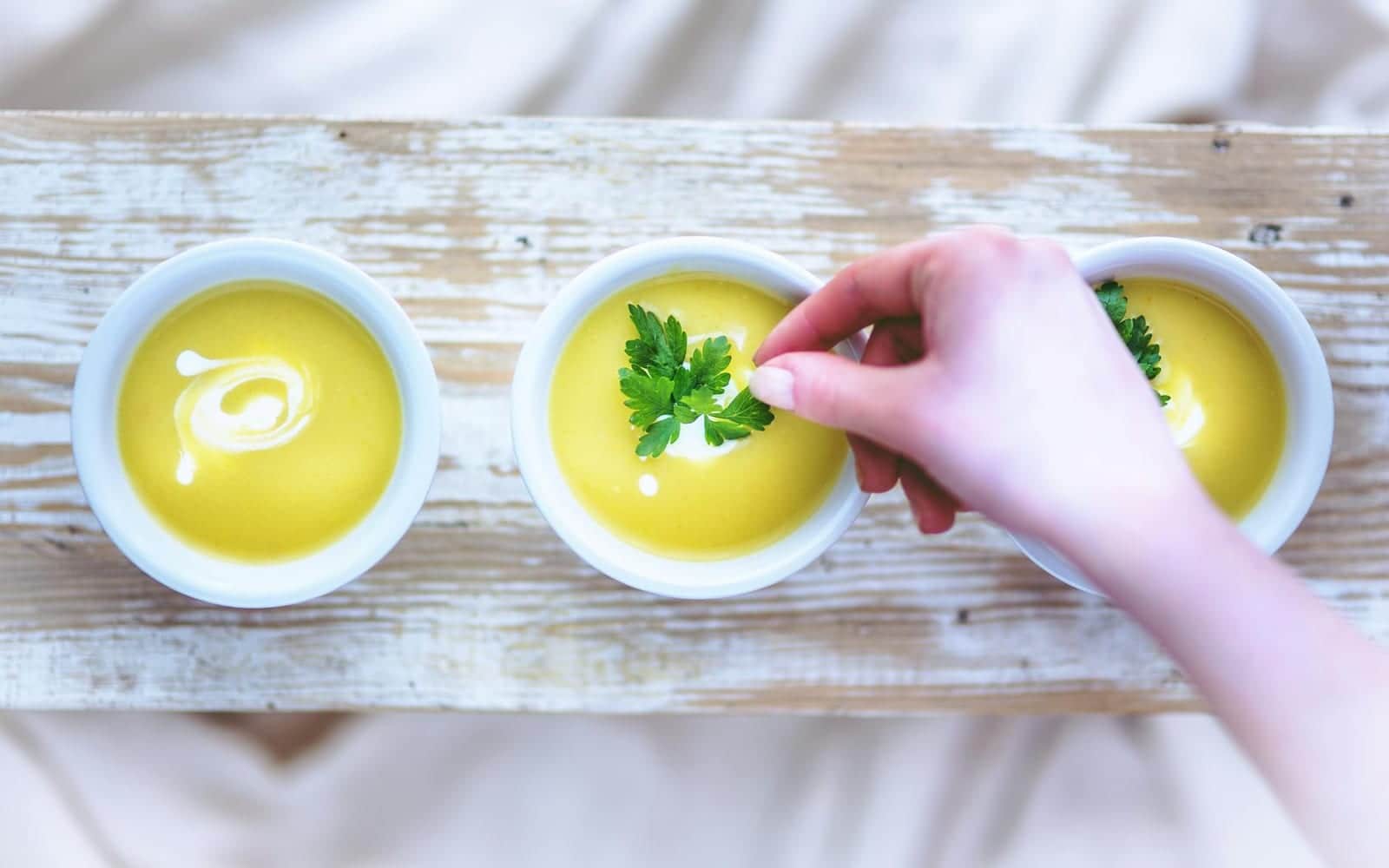 Creamy baked potato soup bowls being garnished with herbs