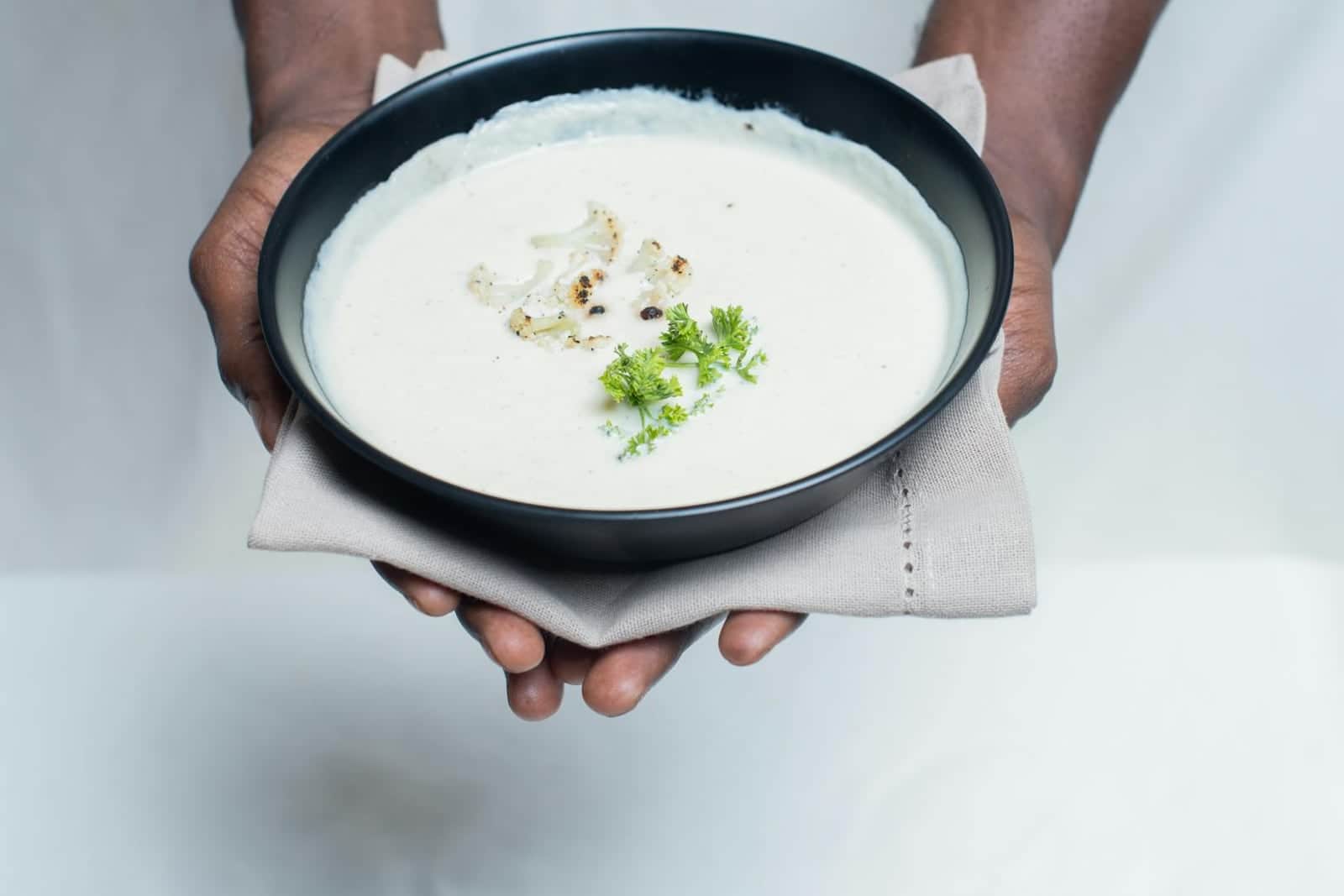 Creamy cauliflower leek soup in a black bowl with parsley garnish