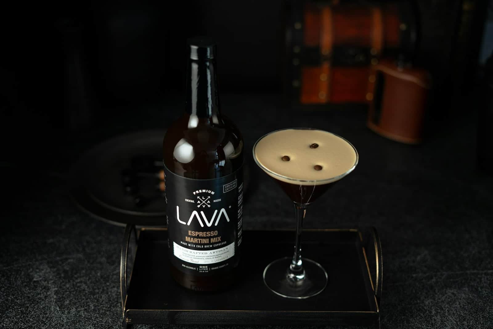 Espresso martini cocktail in a coupe glass with coffee foam and a dark bottle nearby