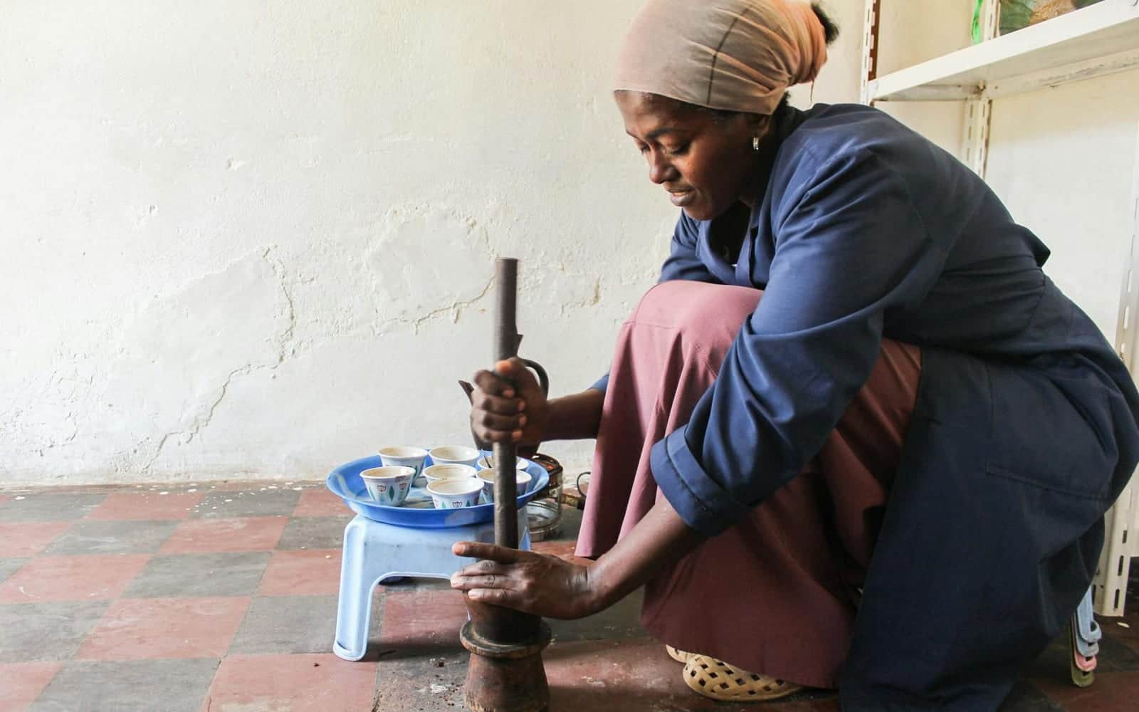 Ethiopian coffee ceremony preparation with coffee being ground by hand