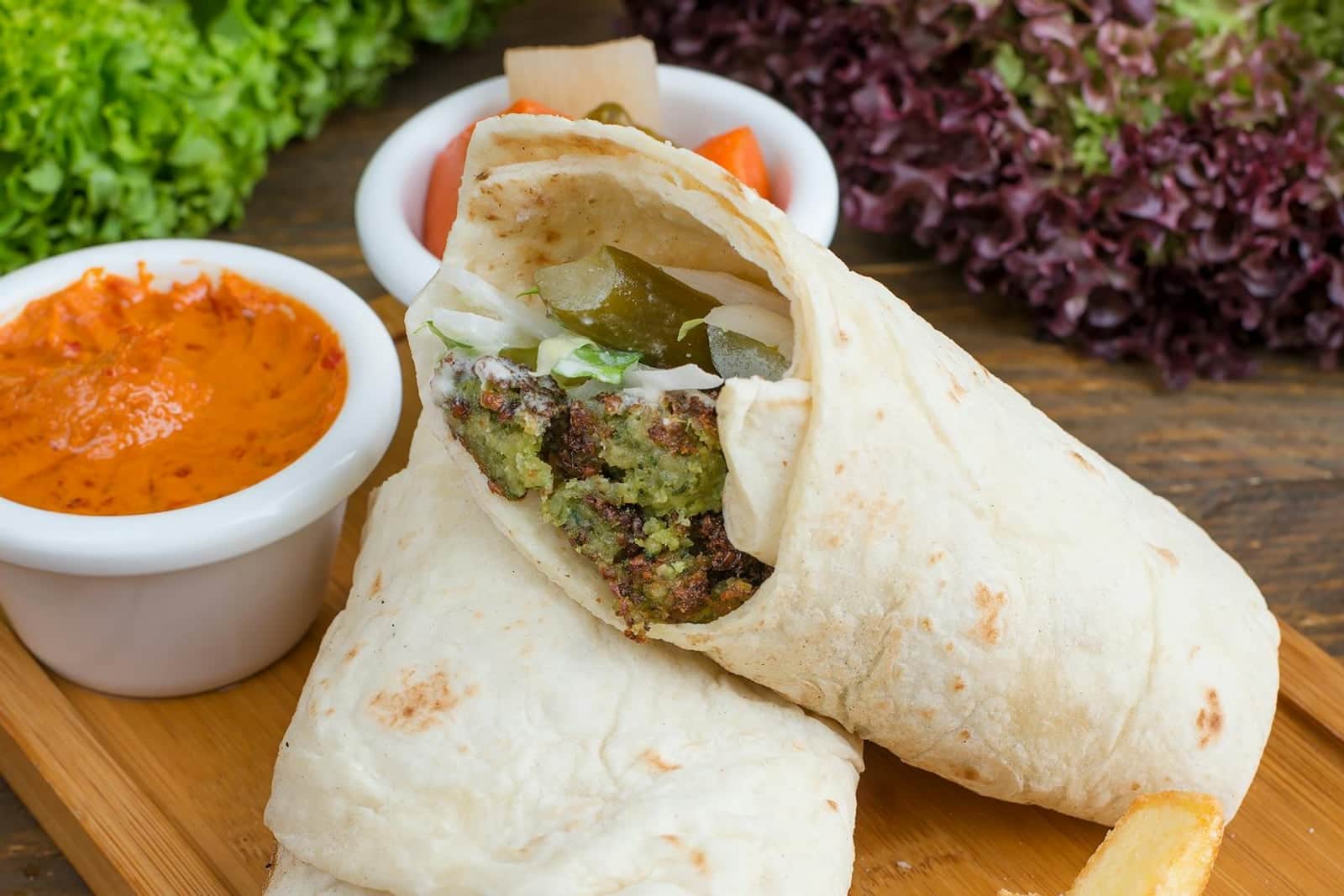 Falafel pita wrap with sauce, vegetables, and crisp falafel filling