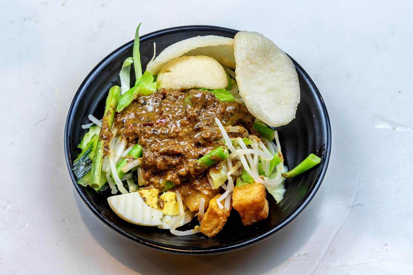 Indonesian gado gado salad bowl with vegetables, tofu, peanut sauce, and crisp garnish