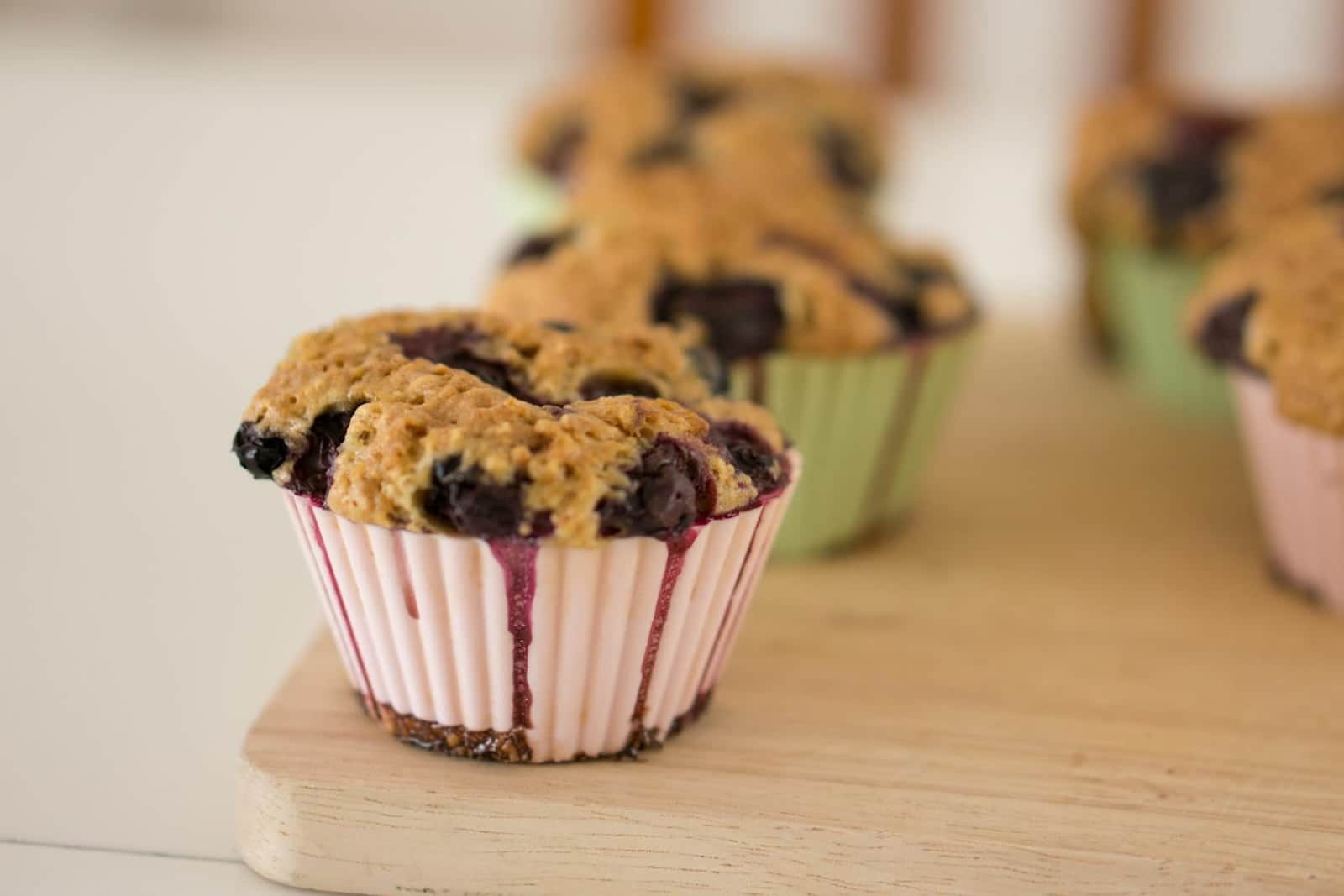 Gluten-free blueberry muffin-style muffins baked in paper cups on a wooden board