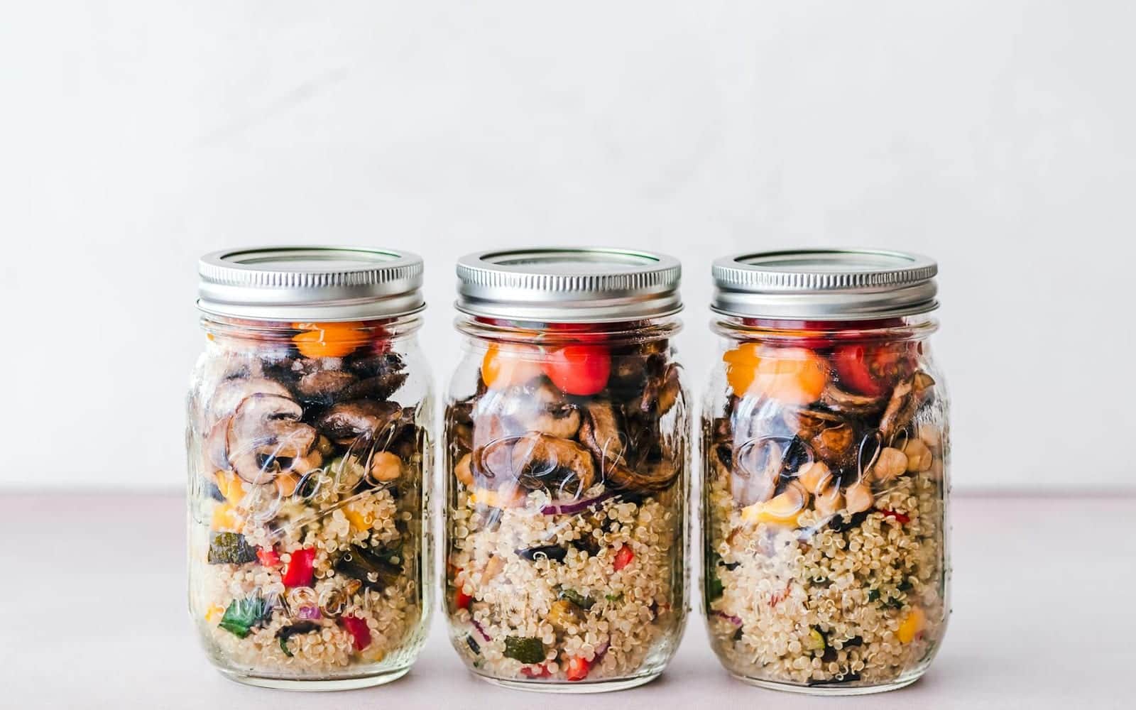 Grain salad meal prep jars with quinoa, roasted vegetables, and beans