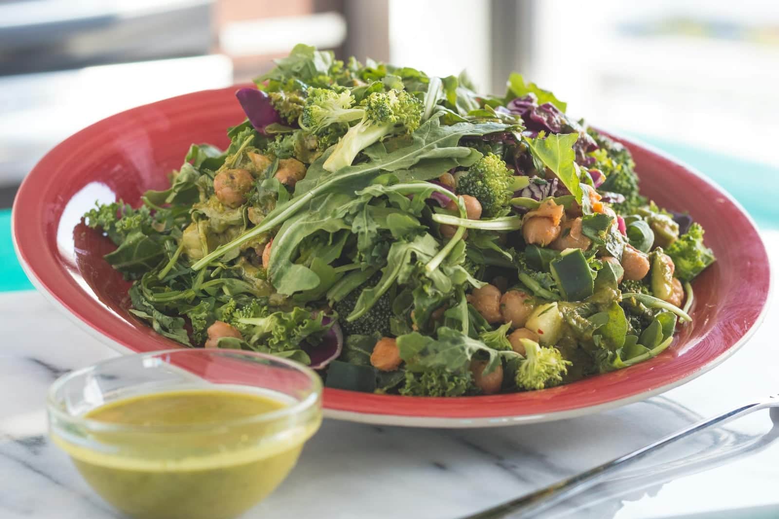 Kale Caesar salad with crispy chickpeas and green dressing on a red plate