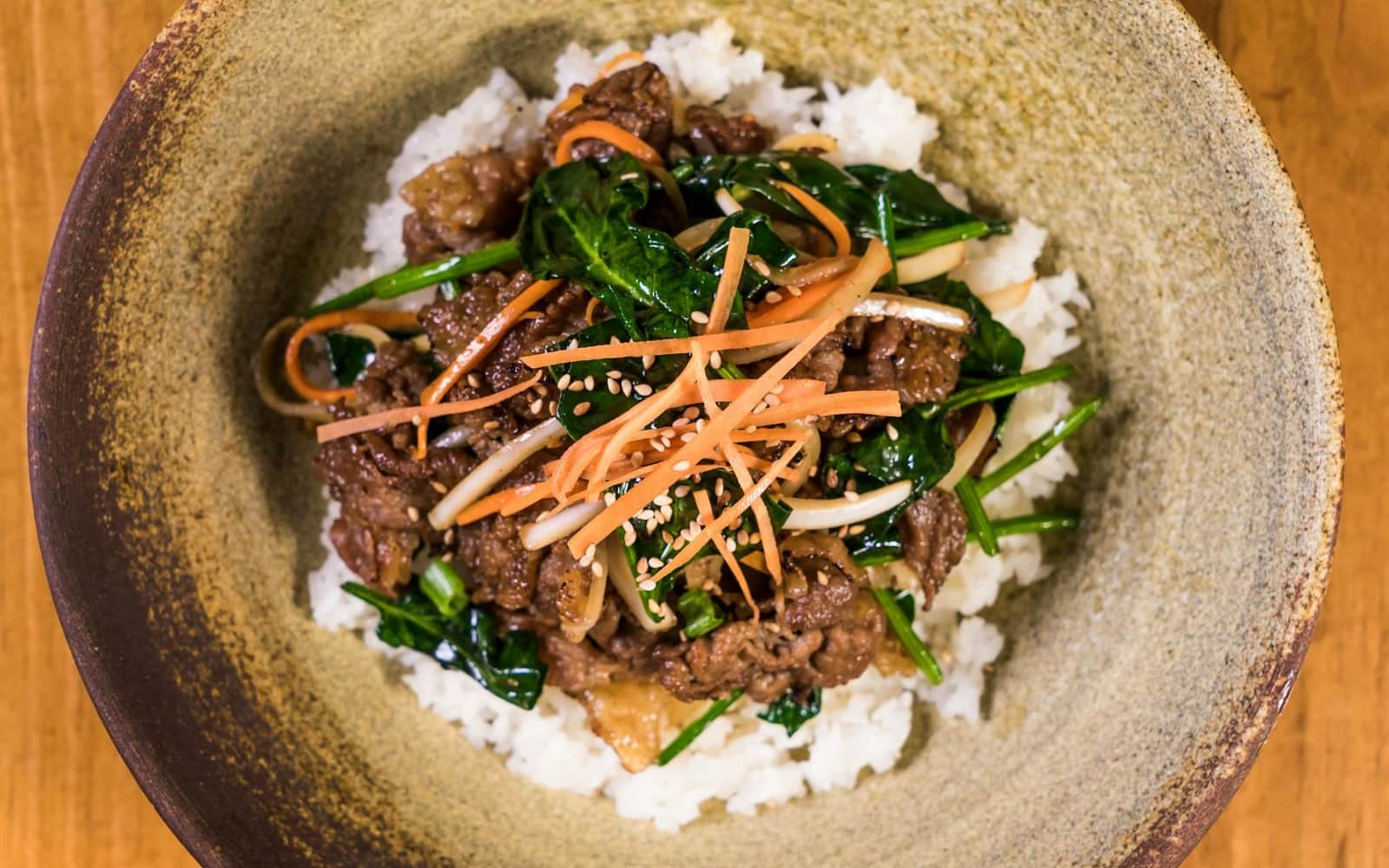 Korean beef bulgogi bowl with rice, vegetables, scallions, and glossy marinated beef