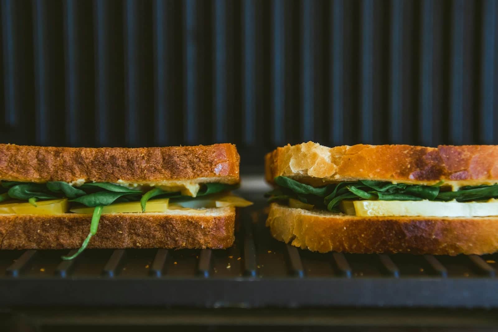 Kimchi grilled cheese sandwiches toasting on a grill with browned bread and green filling