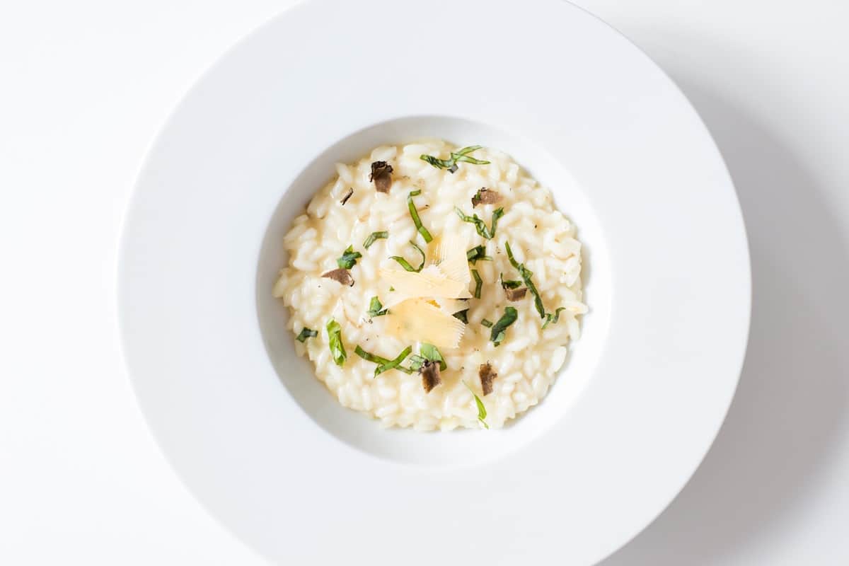 Creamy mushroom risotto on a white plate with herbs and Parmesan