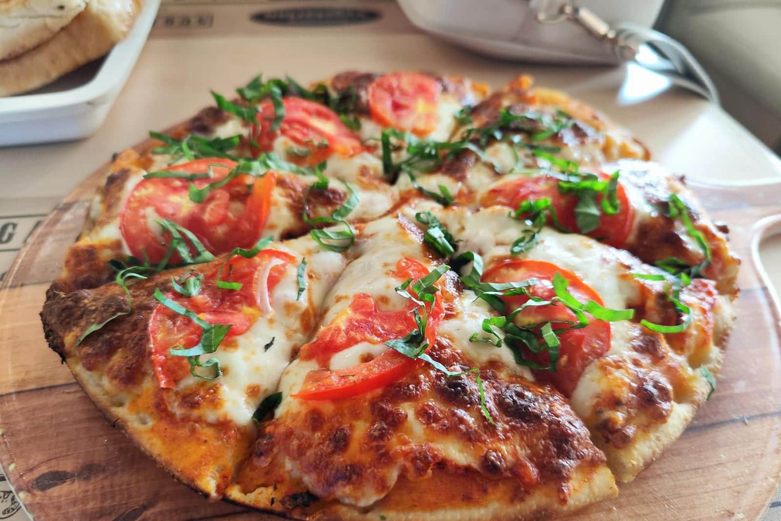 Pizza Margherita Napoletana with tomato, mozzarella, basil, and a blistered crust on a wooden board