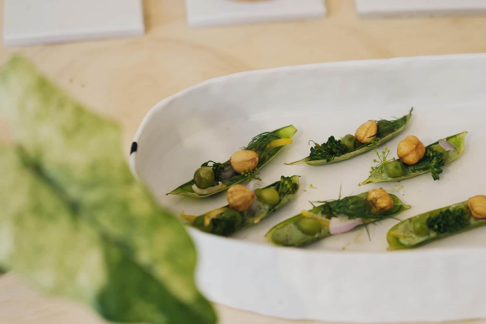 Spring pea ricotta crostini-style bites with peas, greens, and toasted toppings on a white platter