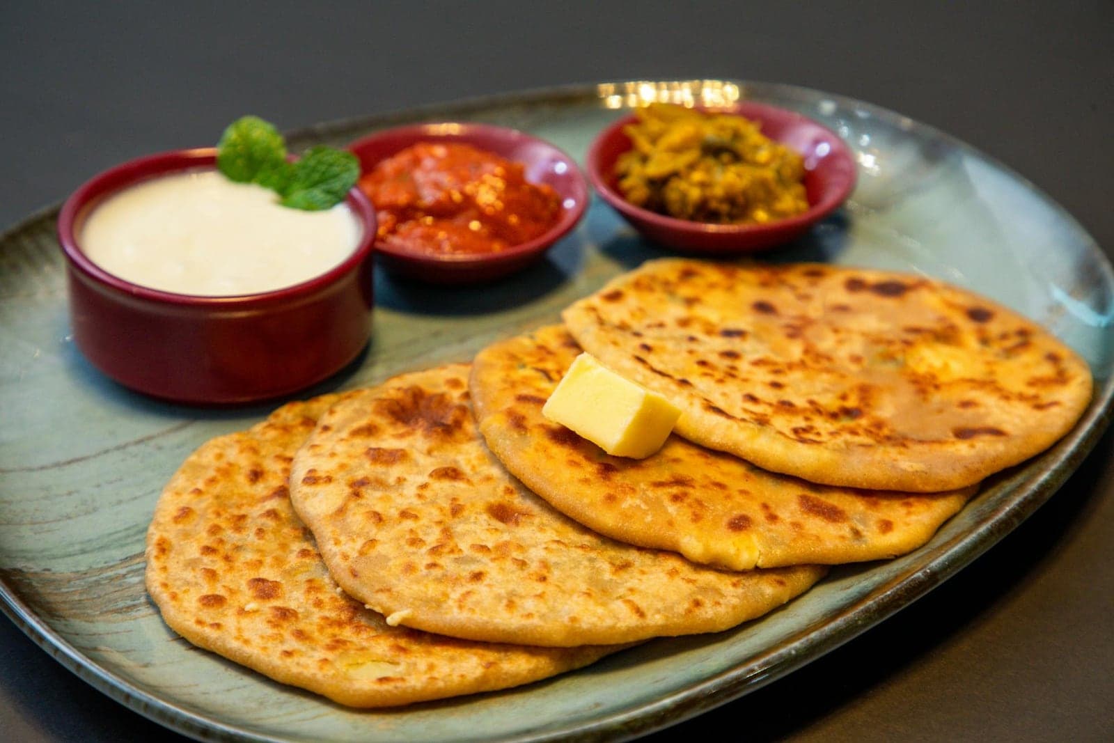Aloo paratha Indian flatbread served with yogurt, pickles, and butter
