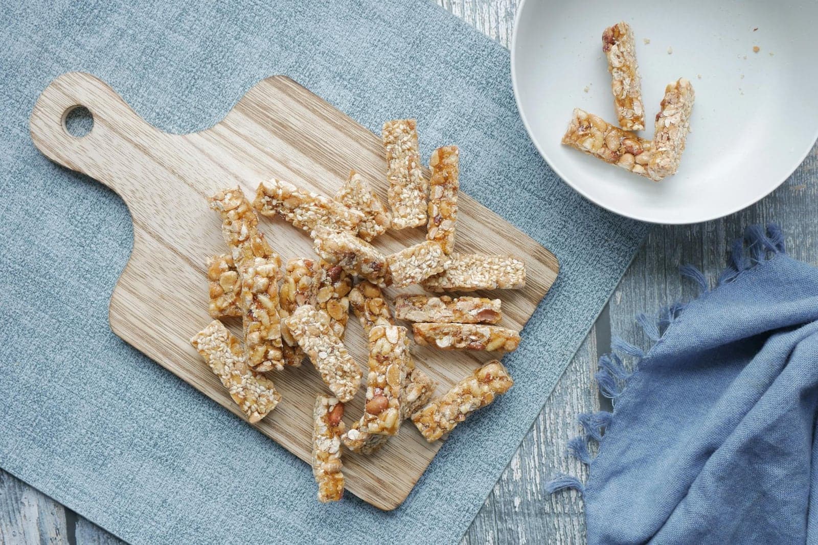 Peanut butter oat bars cut into sticks on a wooden board with a small white bowl