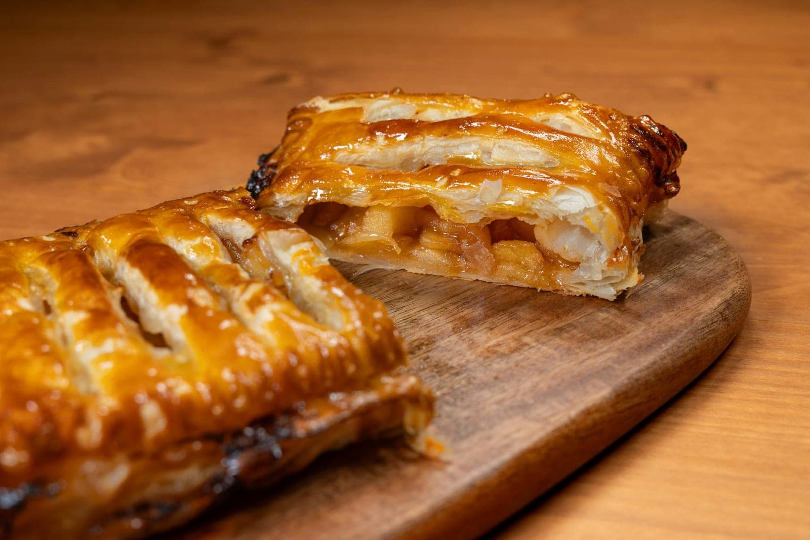 Apple turnovers with golden flaky pastry and apple filling on a wooden board