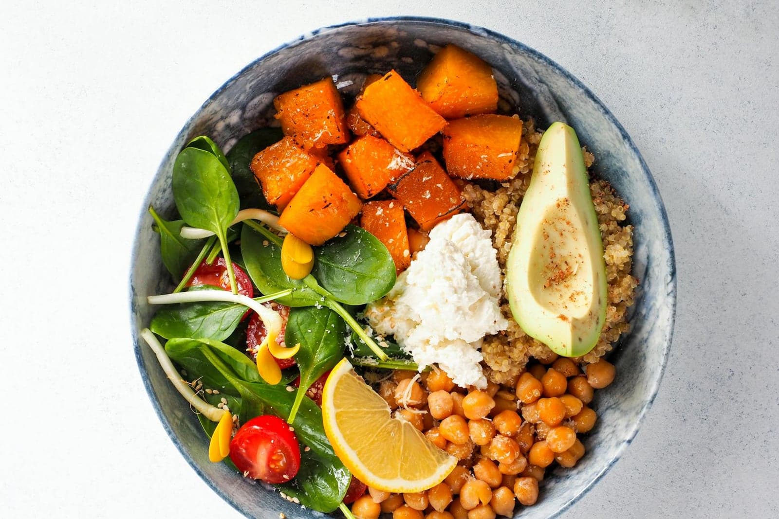 Asian Buddha bowl with sweet potato, chickpeas, avocado, greens, lemon, and grains