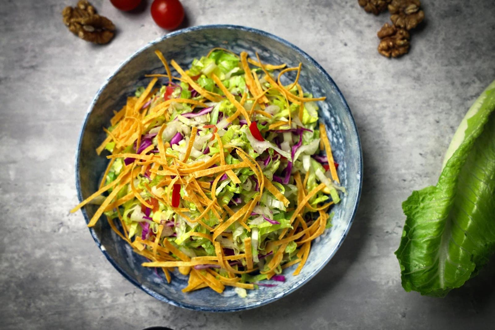 Asian sesame slaw with shredded vegetables and herbs in a blue bowl