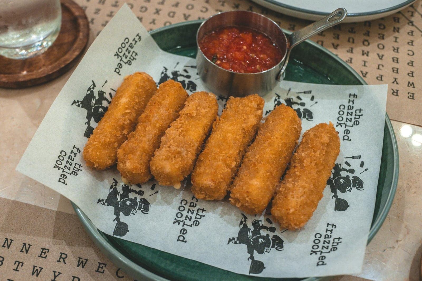 Baked mozzarella sticks with marinara dipping sauce on a restaurant plate