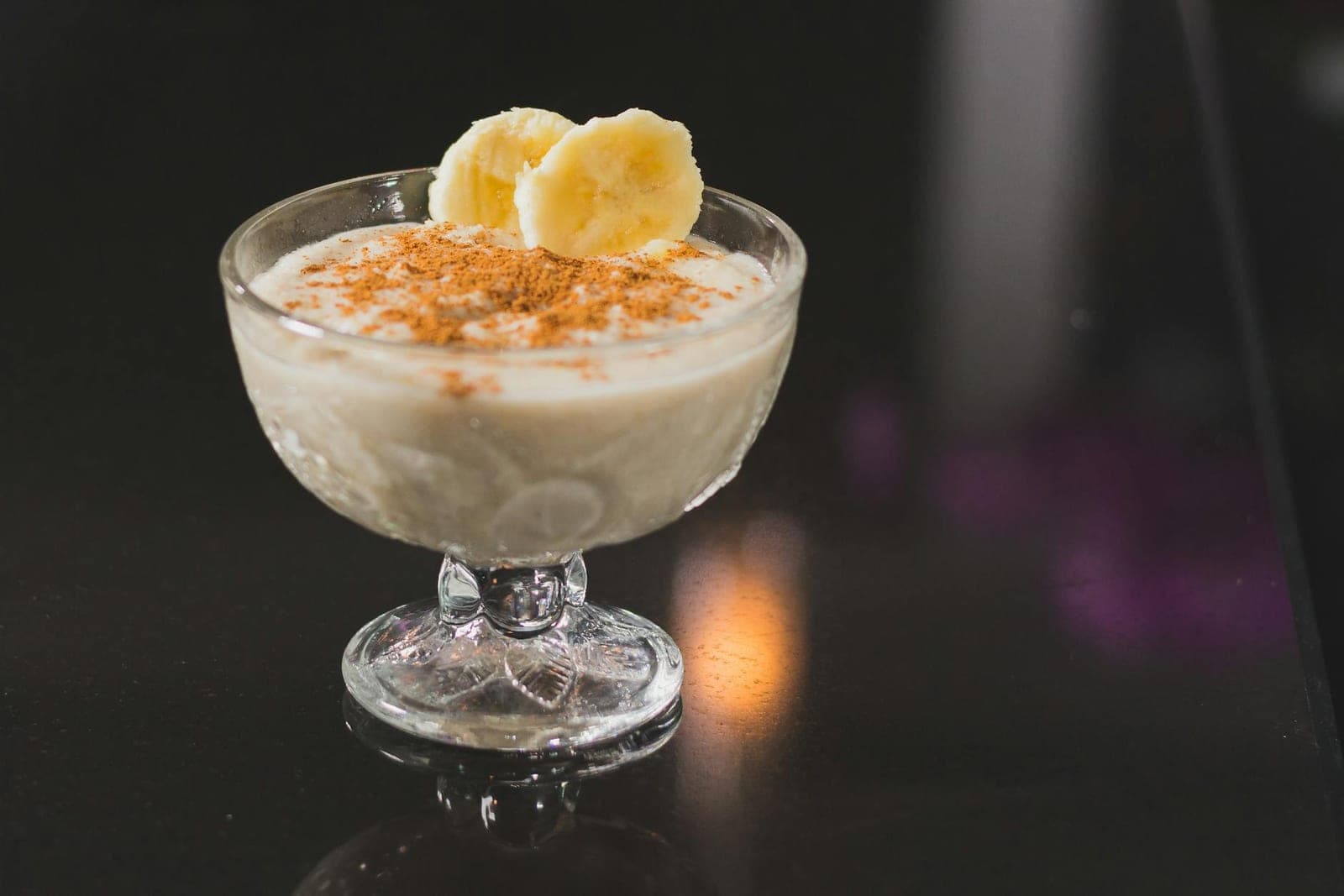 Banana nice cream dessert in a stemmed glass with cinnamon on top