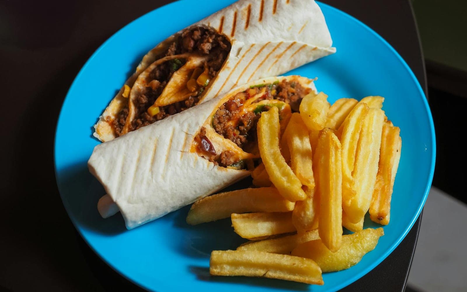 Family beef and bean burritos with fries served on a blue plate