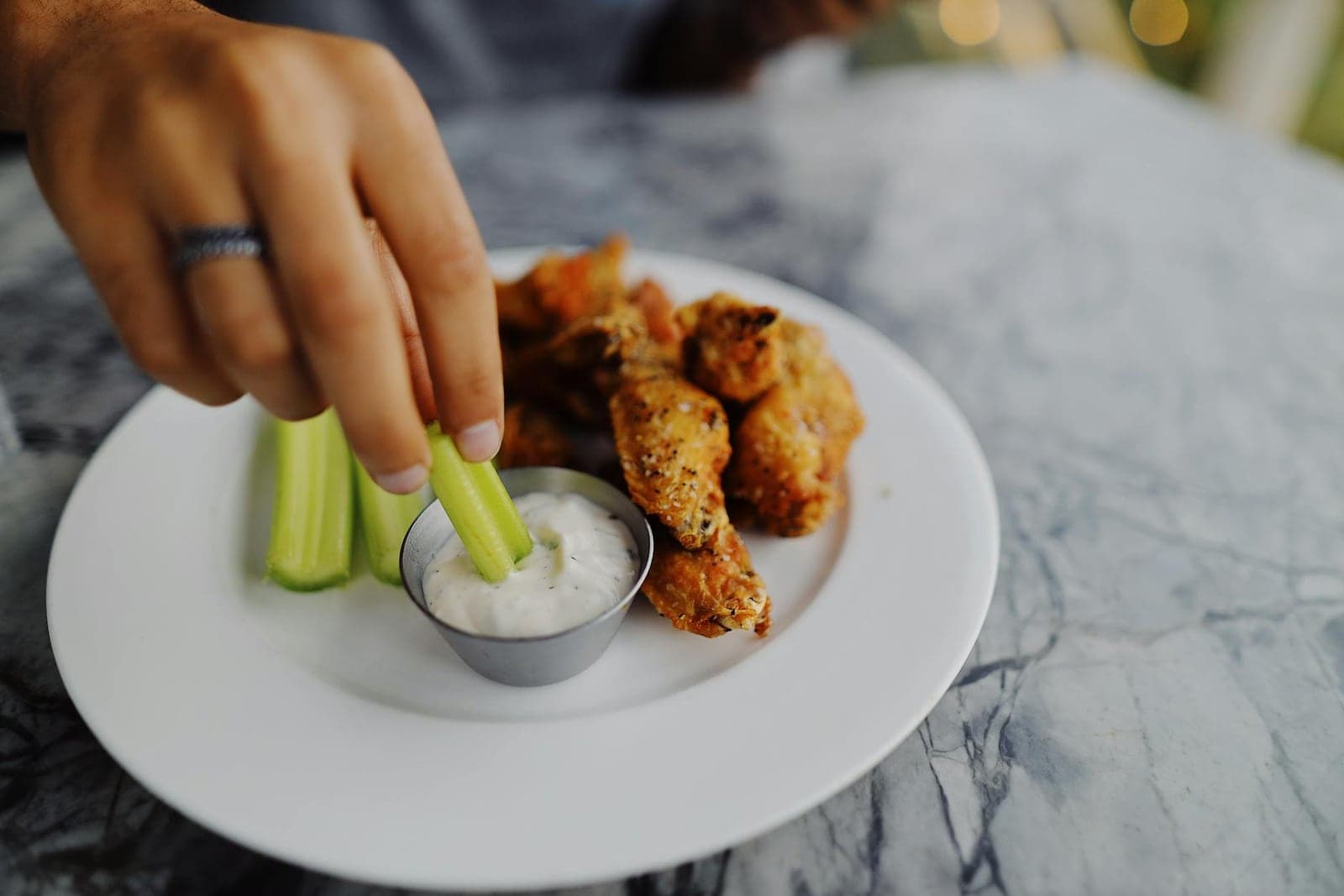 Buffalo chicken dip setup with celery, creamy dip, and spicy chicken pieces on a plate