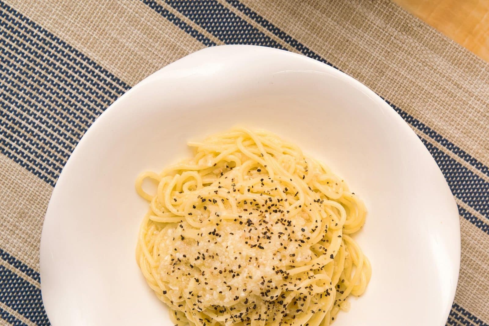 Cacio e pepe pasta twirled with cheese and black pepper on a white plate