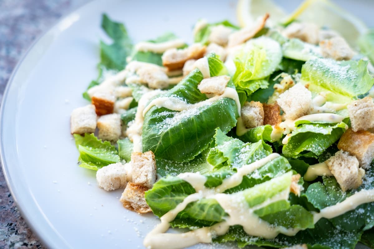 Classic Caesar salad with romaine lettuce, croutons, shaved Parmesan, and creamy dressing on a plate