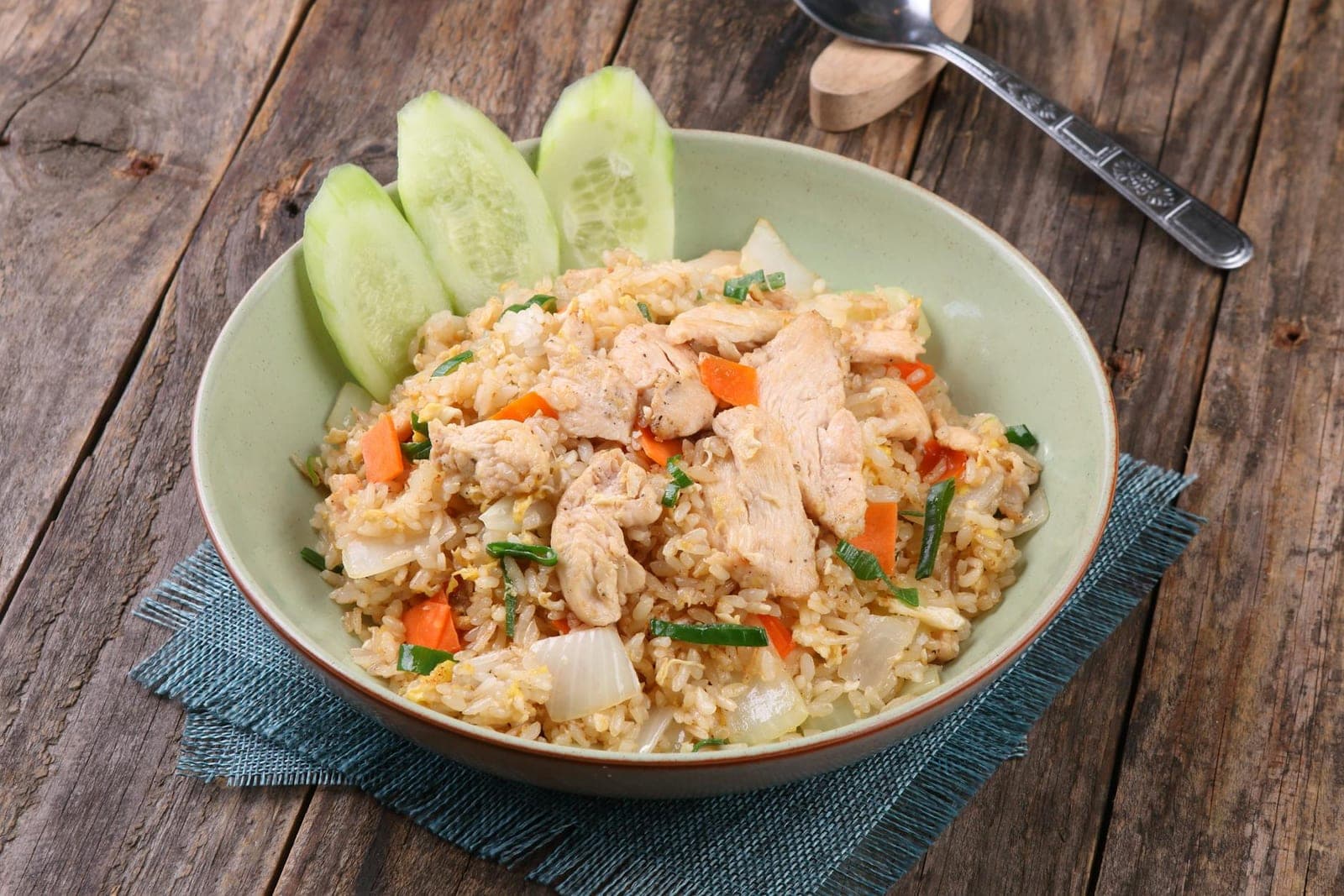 Chicken fried rice with diced chicken, vegetables, and rice in a green bowl