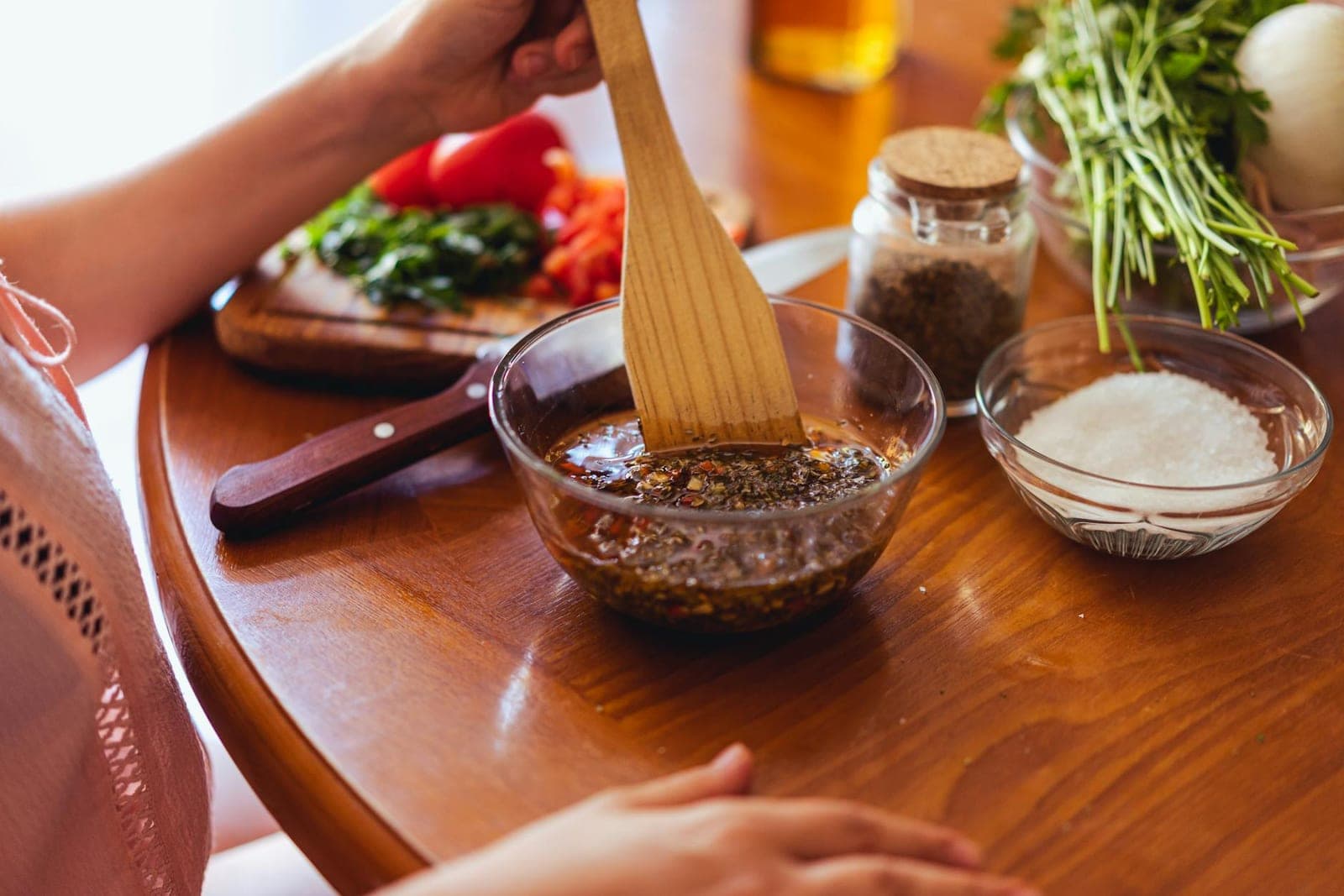 Chimichurri sauce being mixed with fresh herbs and spices in a glass bowl