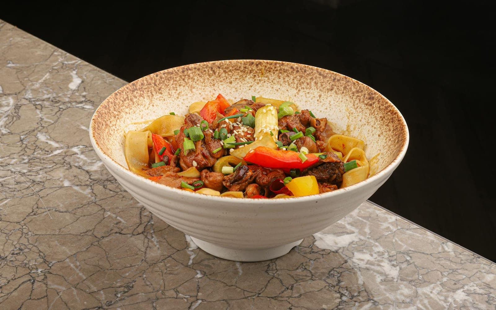 Chinese black pepper beef noodles with peppers and beef in a white bowl