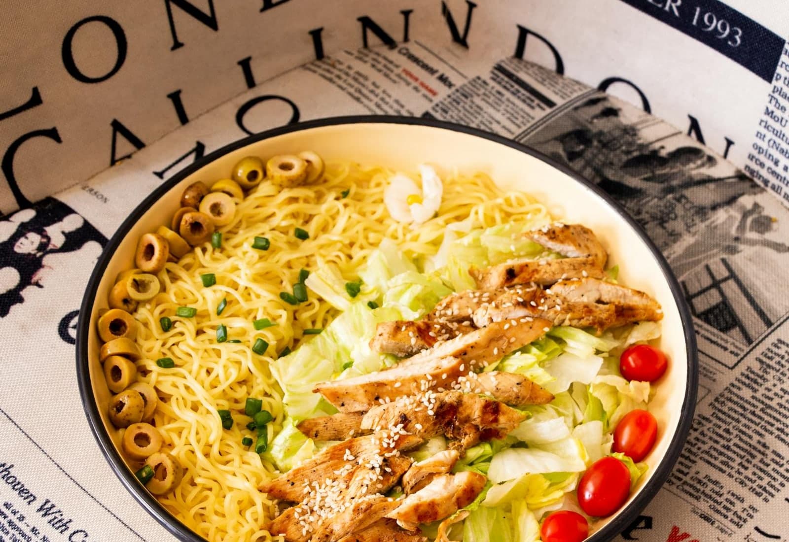 Chinese chicken salad-style bowl with sliced chicken, noodles, greens, and cherry tomatoes