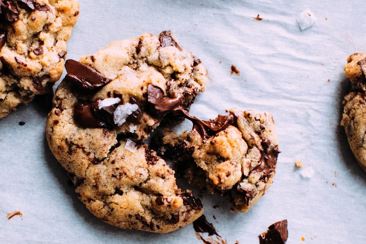 Stack of thick chocolate chip cookies with melted chocolate pools and flaky sea salt on top