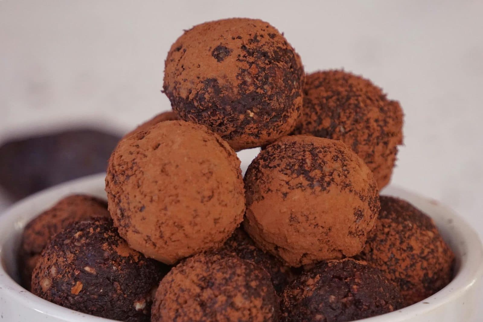 Chocolate truffles coated in cocoa powder and stacked on a white plate