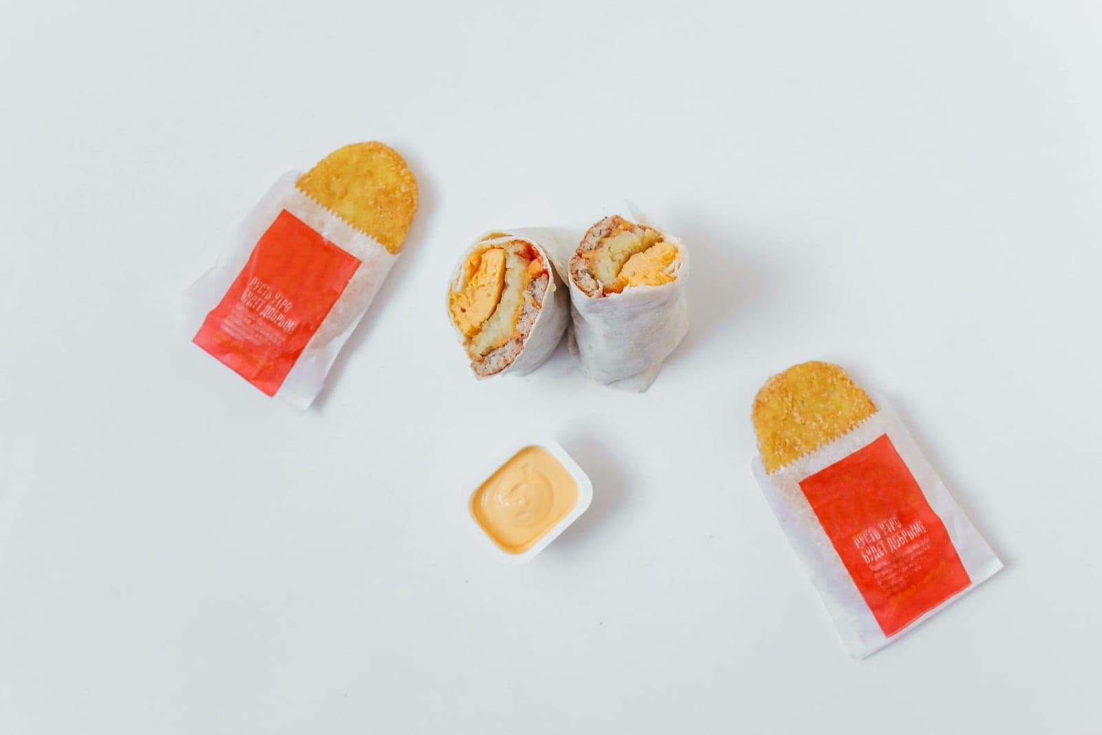 Breakfast burrito halves with eggs, sauce, and crisp hash browns on a white surface