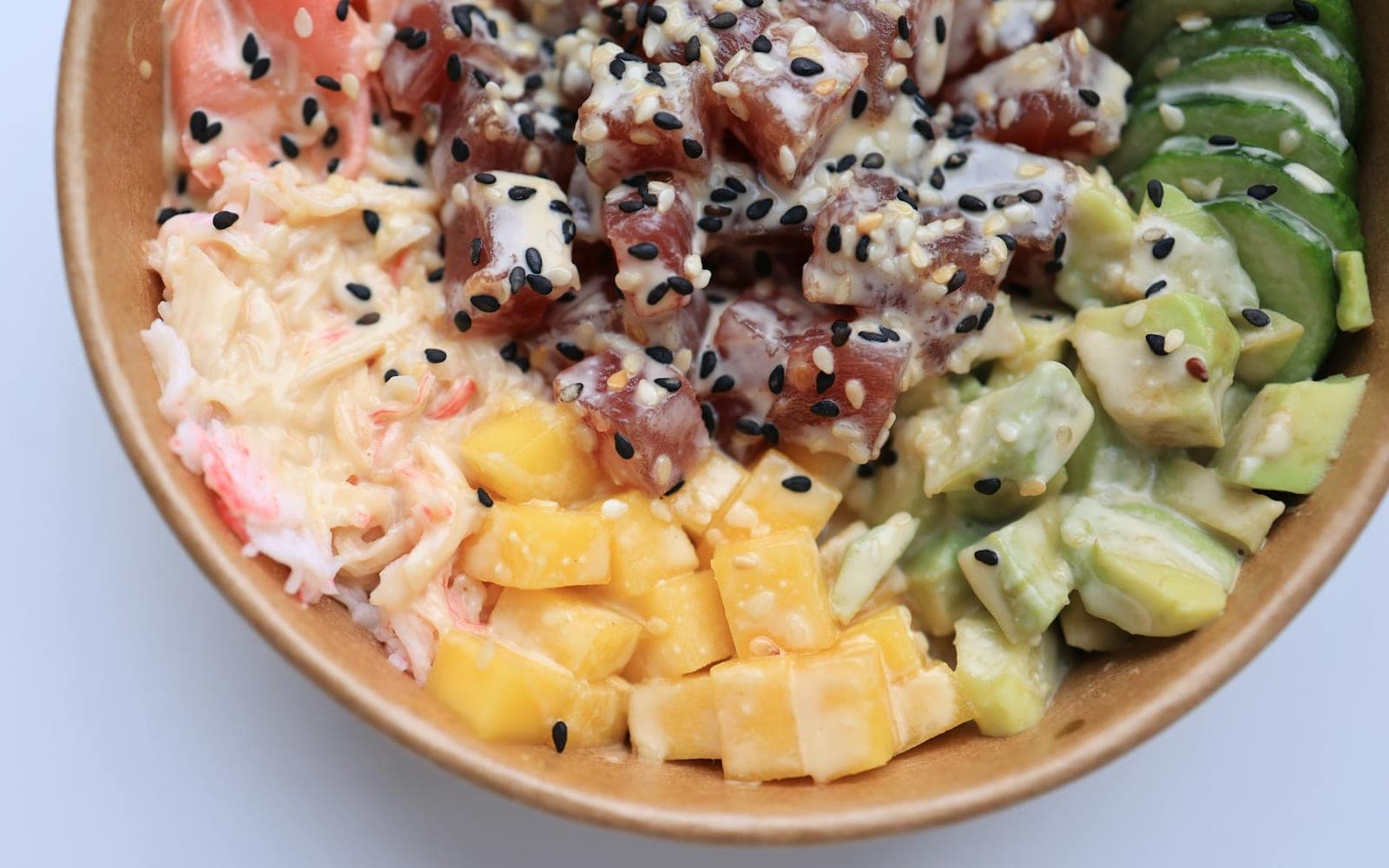 Classic ahi poke bowl with tuna, avocado, mango, cucumber, rice, and sesame