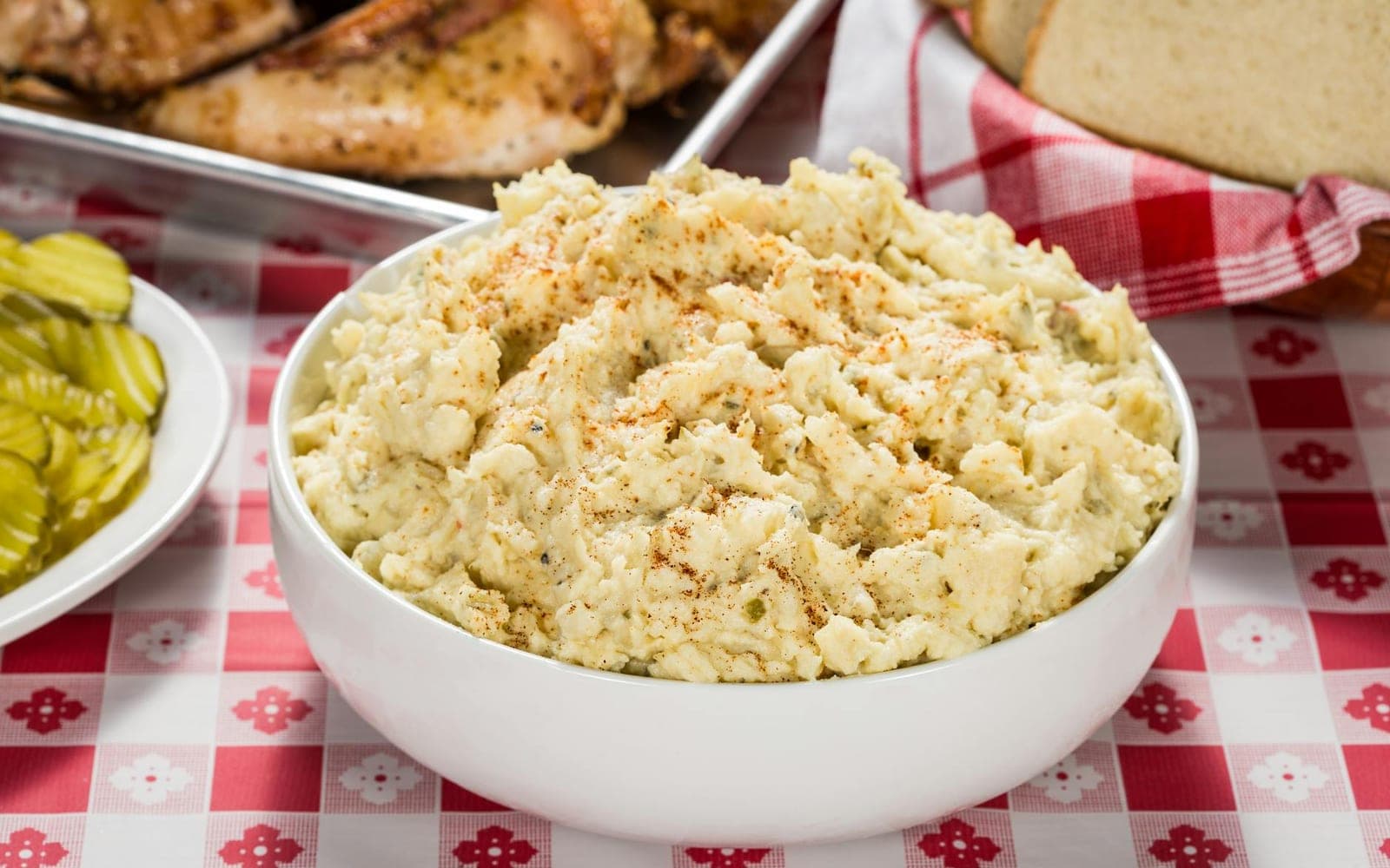 Classic American potato salad in a white bowl on a checkered picnic table