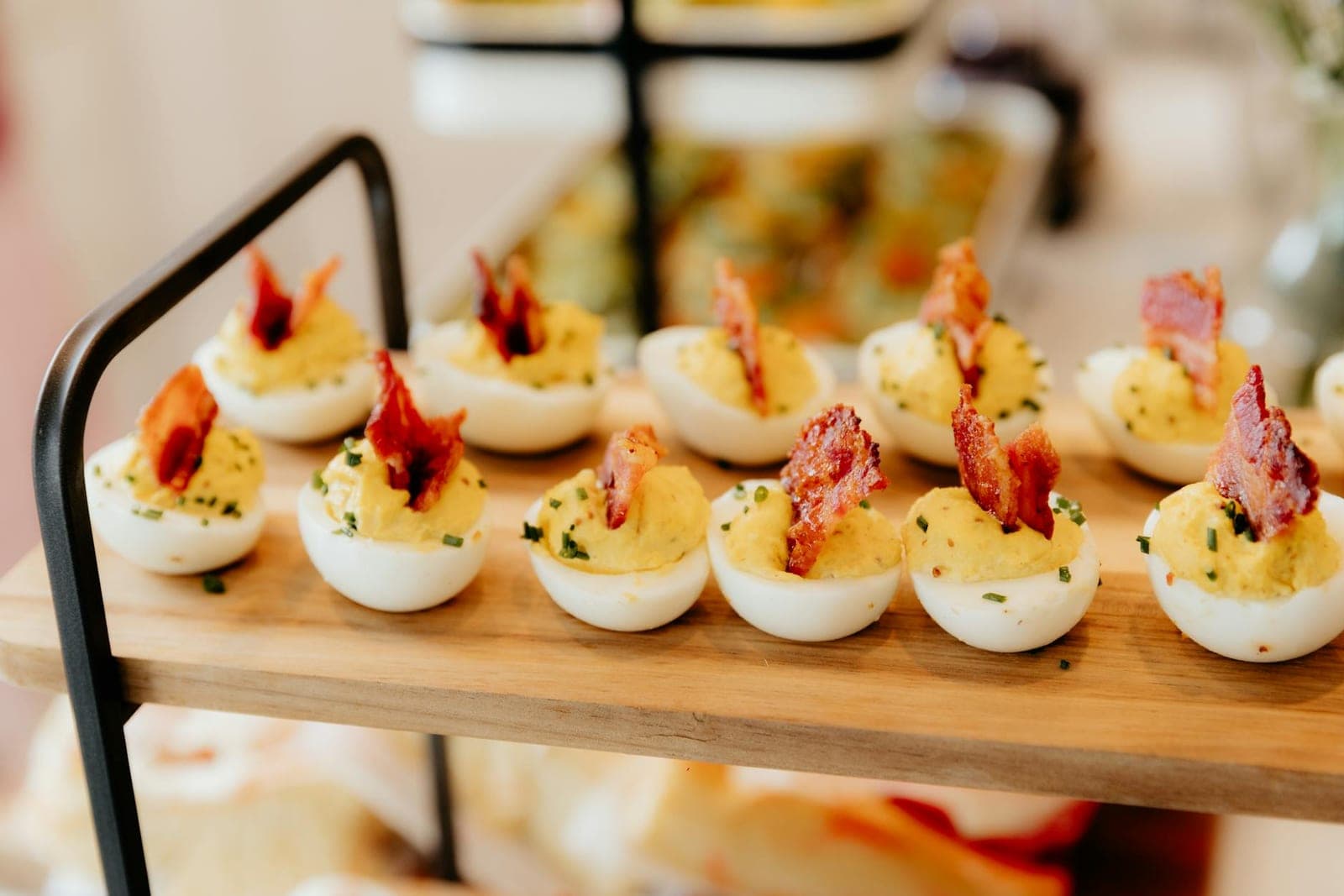 Classic deviled eggs topped with paprika and bacon pieces on a party tray
