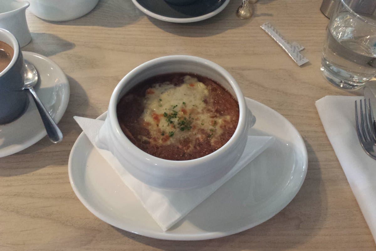 Bowl of French onion soup with melted Gruyere cheese bubbling on top of a baguette crouton