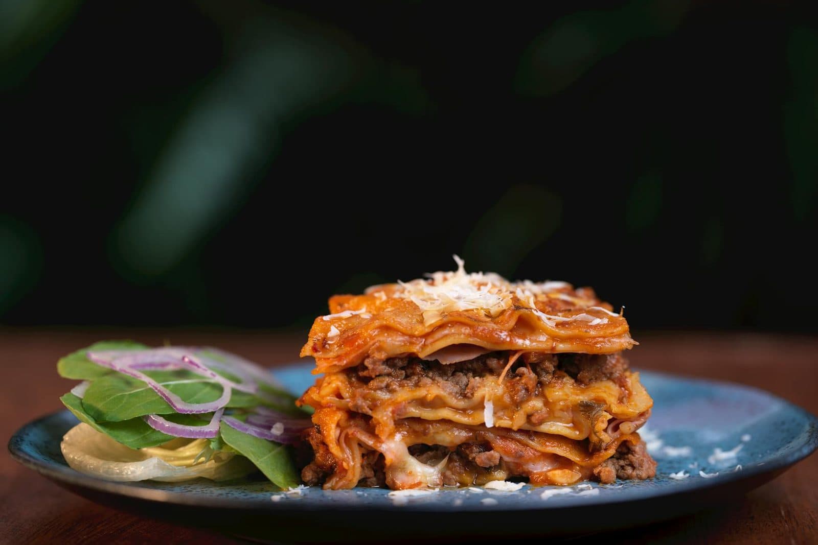 Classic meat lasagna slice with layers of pasta, sauce, cheese, and a small side salad