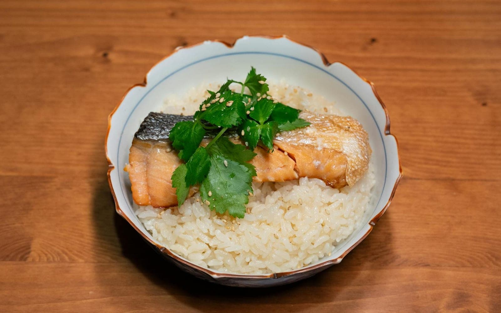 Clean eating salmon bowl with salmon, rice, herbs, and vegetables