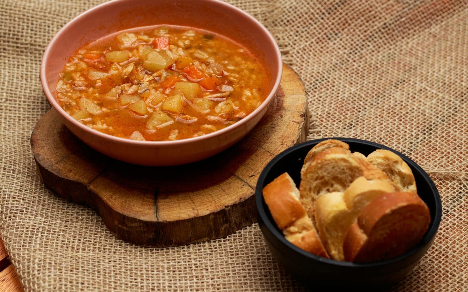 Detox vegetable soup in a brown bowl with bread on a rustic surface