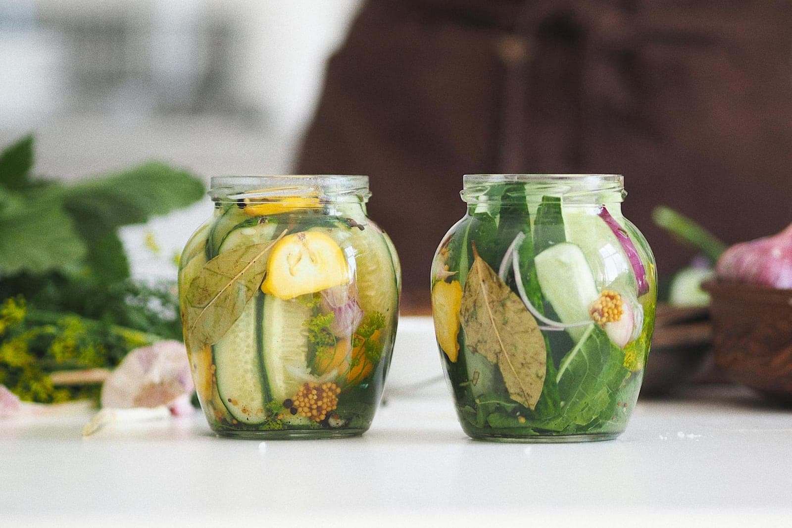Homemade dill pickles packed in glass jars with cucumbers, herbs, and brine