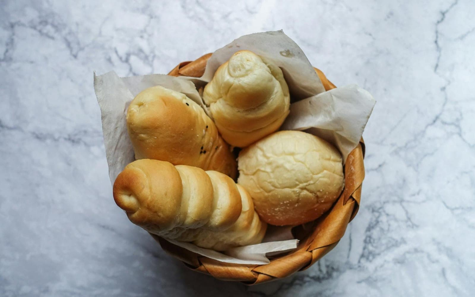 Dinner rolls and soft breads arranged in a wicker basket