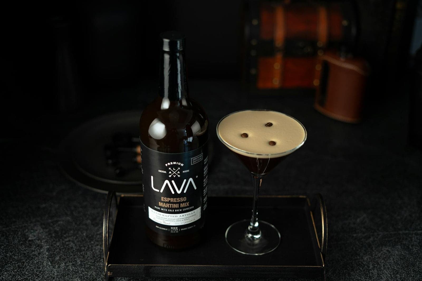 Espresso martini cocktail in a coupe glass with coffee foam and a dark bottle nearby